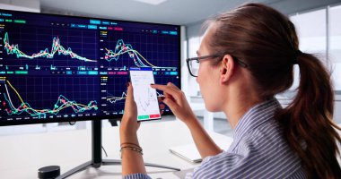 Dizüstü bilgisayardaki ve akıllı telefon uygulamasındaki pazar eğilimlerini analiz eden başarılı bir borsacı..