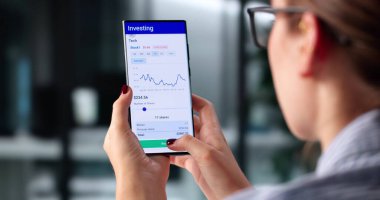 Akıllı Kadın Komisyoncu Borsa Grafiklerini Analiz Etmek İçin Ticaret Uygulaması Kullanıyor.