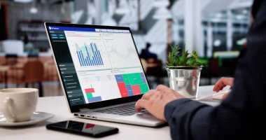 İşadamı Cafe 'deki Laptop' ta Veri Tablolarını Analiz Ediyor