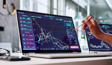 Genç Afrikalı Amerikalı Kadın Dizüstü bilgisayar ekranında hisse senedi grafiklerini analiz ediyor.