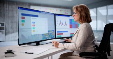 Kıdemli Analizci, Bilgisayarda Mali Verileri Kullanarak Piyasa Eğilimleri Öngörüyor. Yaşlı Kadın Analizcilere Danışmanlık Yapıyor