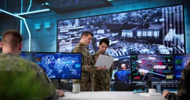 Askerler askeri kontrol merkezindeki verileri izlemek için teknolojiyi kullanıyorlar. Çeşitli geçmişlere sahip birden fazla kişi çalışıyor