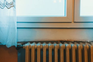 Pencerenin altındaki eski demir radyatör, kaburgalara odaklan..