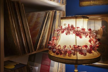 Eski bir dekoratif lambanın ayrıntıları, içinde plak plakları olan bir dolabın yanında, bir oturma odasında kişisel müzik albümleri koleksiyonu..