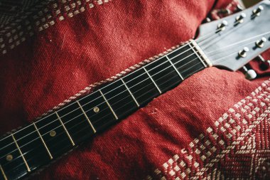 Archtop jazz acoustic guitar on red sofa, vintage look with focus on strings. clipart