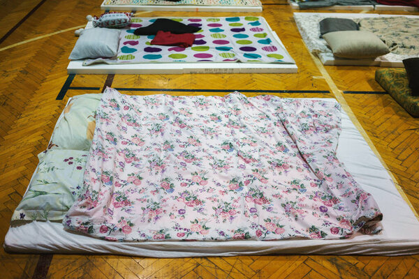 An improvised bed for two on the parquet floor. Styrofoam as a base with sheets and pillows ready for sleeping.