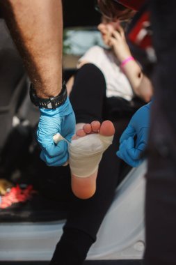 Bir doktor, uzun bir yürüyüşten nasırları tedavi eden yaralı bir kızın bacağını bandajlıyor..
