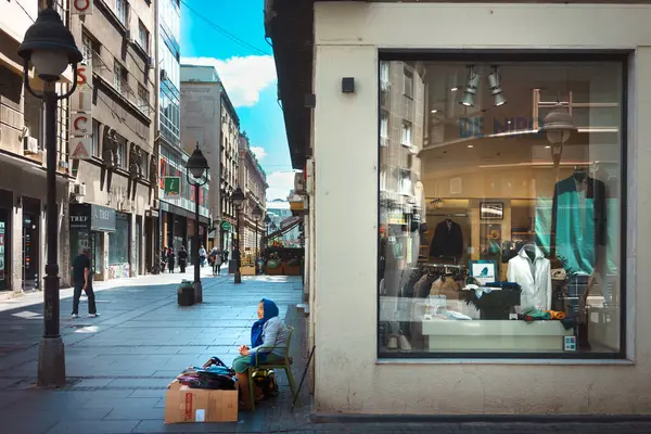 Belgrad, Sırbistan - 14 Mayıs 2025: Şehir merkezinde yaşlı bir kadın sokakta bir şeyler satıyor.