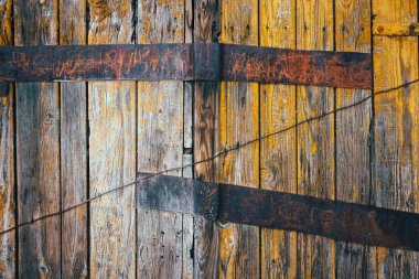 Paslı metal bir levha ile sarı renge boyanmış eski ahşap bir duvarın dokusu..