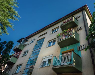 Güzel terasları olan eski bir bina, aşağıdan görülüyor, arka planda temiz bir gökyüzü var..