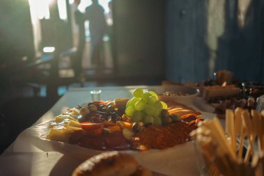 Bir iş toplantısında aperatifler masada, üzümler, kurutulmuş et, peynir, sosis ve zeytin tabakta..