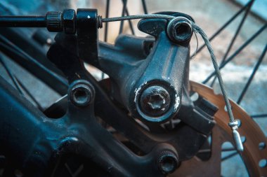 Bisiklet fren mekanizmasının ayrıntıları, tel ve vidaların makro görünümü, arka planda tekerlek kabloları olan disk.