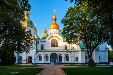Symmetrical view of St Sophia Cathedral in Kyiv, Ukraine, historic orthodox landmark with golden domes, white facade and trees, cultural and spiritual architecture.