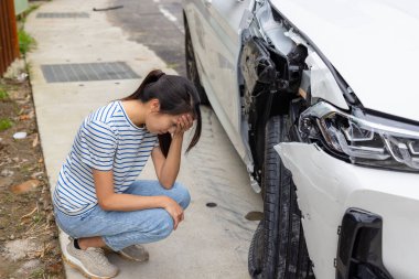 Frightened woman sits in front of crashed car