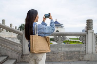 Turist kadın, Tayvan 'daki Chiang Kai Shek Anıt Salonu' nda fotoğraf çekmek için cep telefonu kullanıyor.