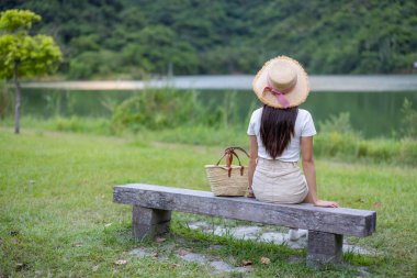Kadın taş bankta otur ve göl manzarasının tadını çıkar.