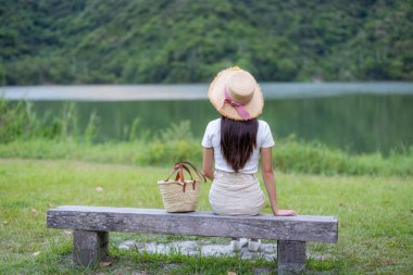 Kadın taş bankta otur ve göl manzarasının tadını çıkar.