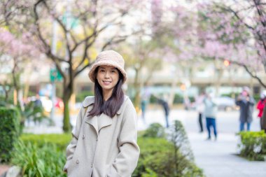 Woman smile to camera with the background of sakura tree