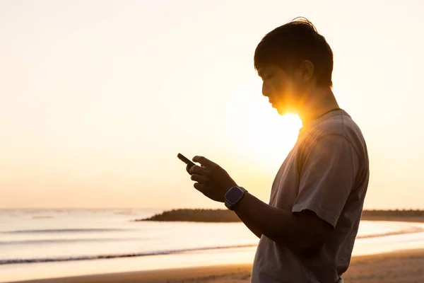 Silhouette Des Menschen Benutzt Handy Bei Sonnenuntergang Strand — Stockfoto