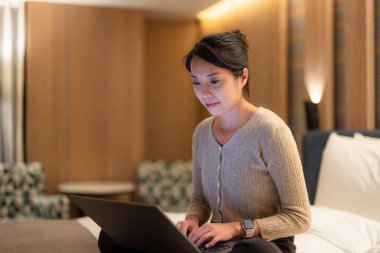 Kadınlar dizüstü bilgisayarda çalışır ve geceleri yatakta otururlar.