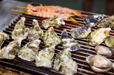 Sokak pazarında metal ağda ızgara istiridye.