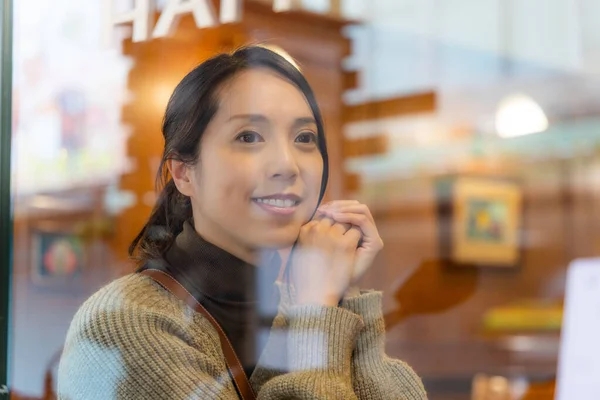 stock image Woman sit inside the coffee shop and look outside the city with window reflection