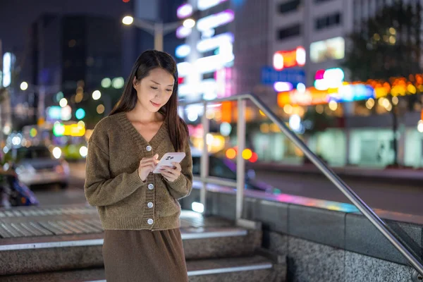 女人在城市中使用移动电话在夜间 — 图库照片
