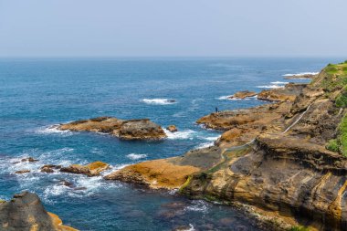 Okyanus dalgaları kayanın üzerinde kırılıyor