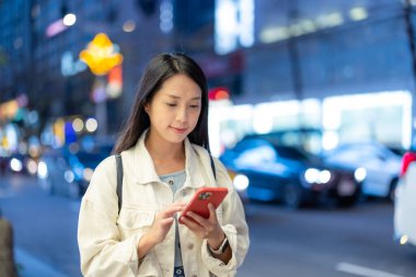 Bayan telefonundaki mesajları kontrol ediyor.,