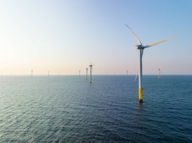 Akşamları denizin üzerinde rüzgar türbini tarlası