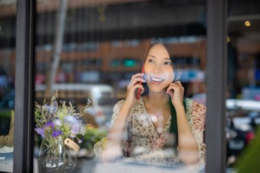 Kadın kahve dükkanında cep telefonuyla konuşuyor.