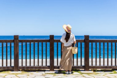 Turist kadın deniz kıyısına bakar.
