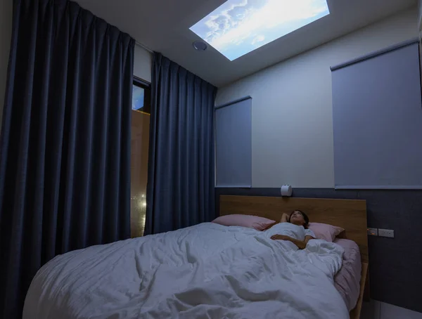 女人躺在床上 看着家里天花板上的视频项目 — 图库照片