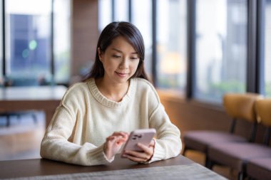 Kadın restoranda cep telefonu kullanıyor. 