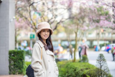 Şehirde kışlık giysileri olan ve kameraya gülümseyen bir kadın.