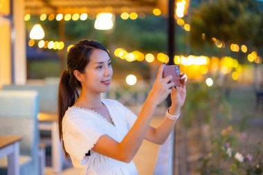 Kadın şehirde fotoğraf çekmek için cep telefonu kullanıyor.