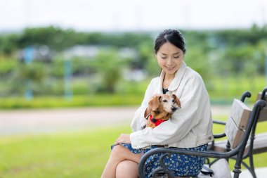 Kadın parka gider ve köpeğiyle bankta oturur.