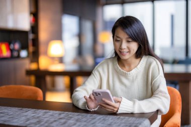 Kadın restoranda cep telefonu kullanıyor.