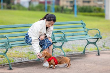 Kadın parkta köpeğini besliyor.