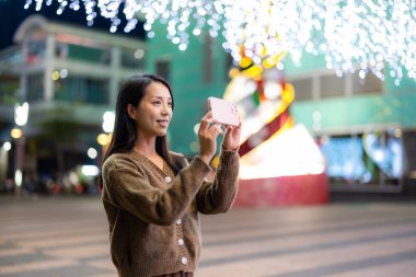 Kadınlar şehirde gece fotoğraf çekmek için cep telefonu kullanırlar.