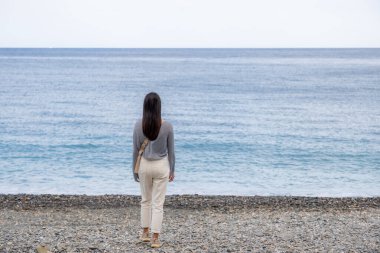 Kadın sahilde duruyor.