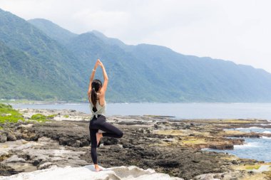 Asyalı kadın pratik yoga sahilde 