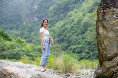 Kadın ormana doğru kayanın üzerinde duruyor.