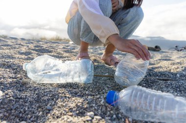Gönüllü plajda plastik şişe çöpü topluyor.