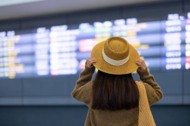 Seyahat eden kadın, ekrandaki uçuş çizelgesine bak.