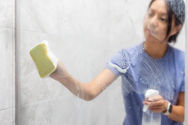 Kadınlar banyodaki sert su lekelerini ve tortuları temizler.