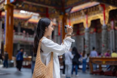 Turist kadın Çin tapınağında fotoğraf çekmek için dijital kamera kullanıyor.