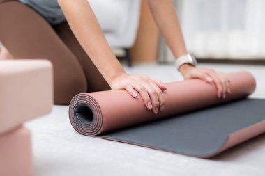 Kadın, yoga minderini kendi elleriyle sardı.