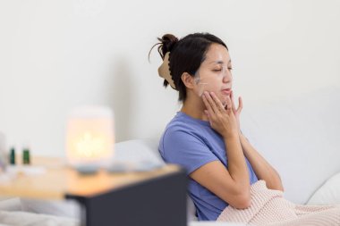 Kadın evde cep telefonu kullanıyor.