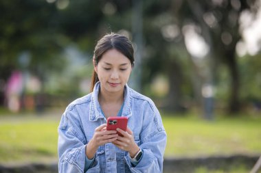 Kadın parkta cep telefonu kullanıyor